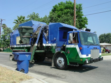 Electric skip hire van parked on Fulham street with recycling bins